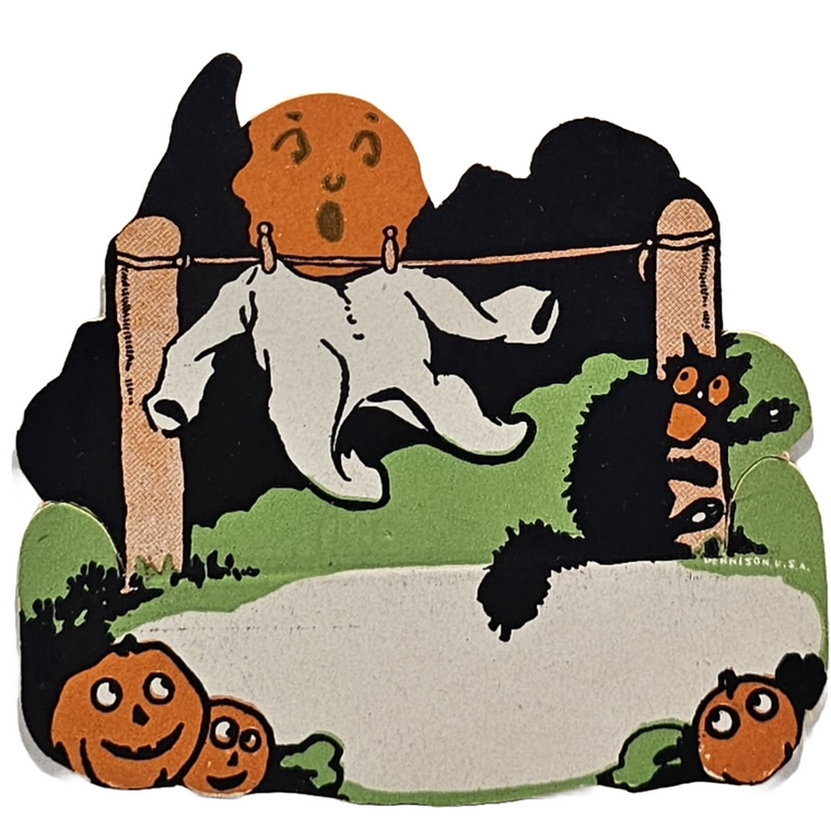 Vintage die-cut place card featuring a pumpkin, ghost, and pajamas design, with a black cat being scared by the ghost, set against a dark background. The place card is from the 1920s.
