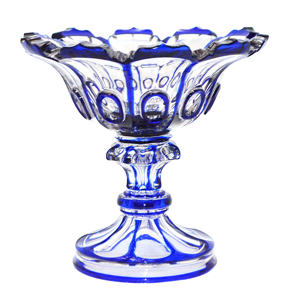 A cobalt blue and clear glass pedestal bowl with a fluted rim and decorative cut patterns, shown on a plain white background.