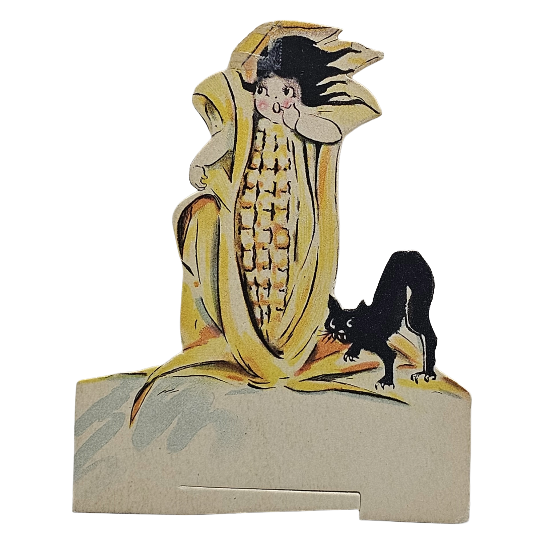 Decorative paper cutout of a corn stalk with a face and a black cat on a white background