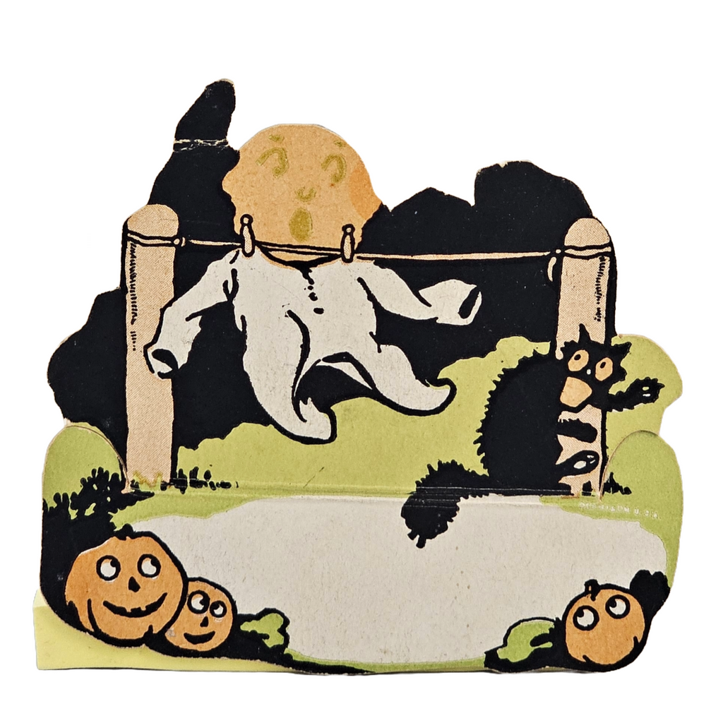 Vintage Halloween-themed die cut place card from the 1920s featuring a ghost in pajamas hanging from a tree with a black cat and a moon in the background.