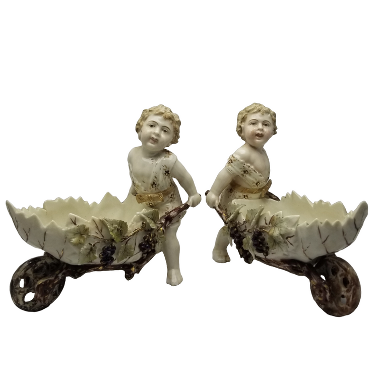 German Porcelain Bisque Garden Cherubs Pair Putti Hand Painted Pushing Wheelbarrows with Moving Wheels Volkstedt Thuringia