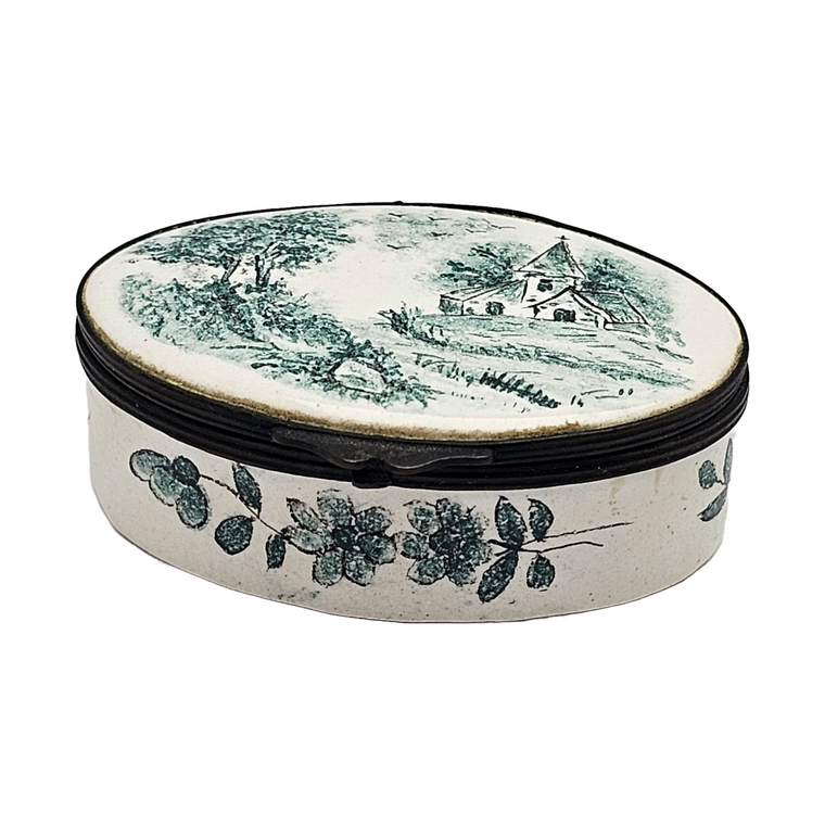 An oval-shaped, hand-painted French Faience trinket jar with a green enamel church scene on the lid and floral patterns around the base.