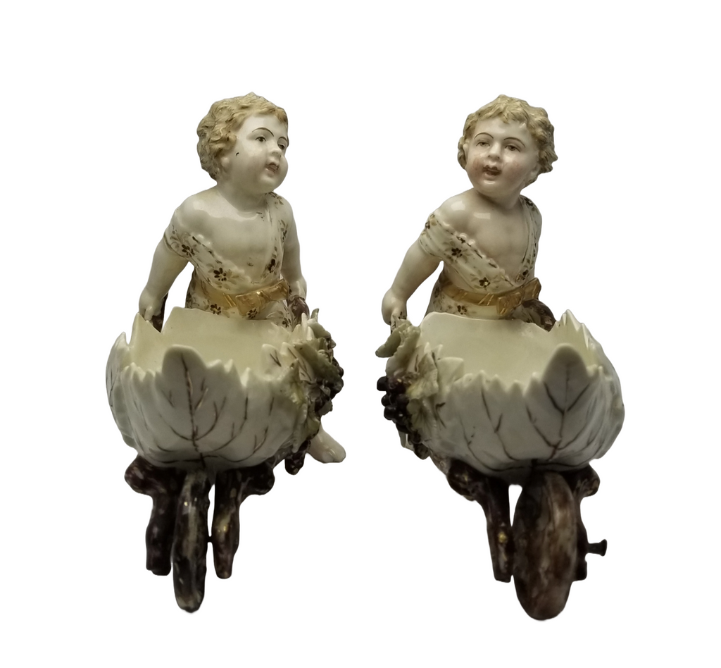 German Porcelain Bisque Garden Cherubs Pair Putti Hand Painted Pushing Wheelbarrows with Moving Wheels Volkstedt Thuringia