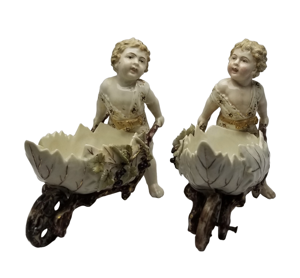 German Porcelain Bisque Garden Cherubs Pair Putti Hand Painted Pushing Wheelbarrows with Moving Wheels Volkstedt Thuringia