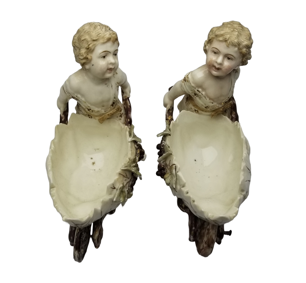 German Porcelain Bisque Garden Cherubs Pair Putti Hand Painted Pushing Wheelbarrows with Moving Wheels Volkstedt Thuringia