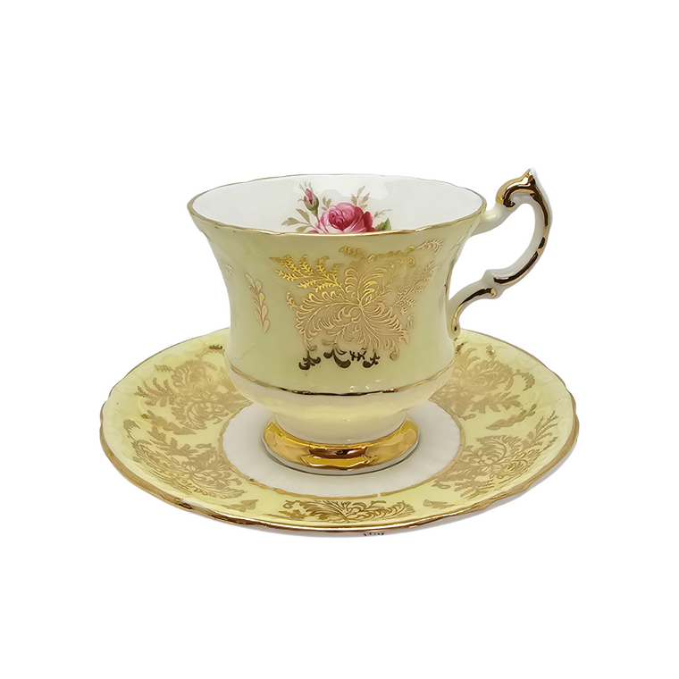 A vintage Royal Albert tea cup and saucer set in pale yellow china with gold floral detailing, a pink rose motif on the cup, and a gold handle, shown on a white background.