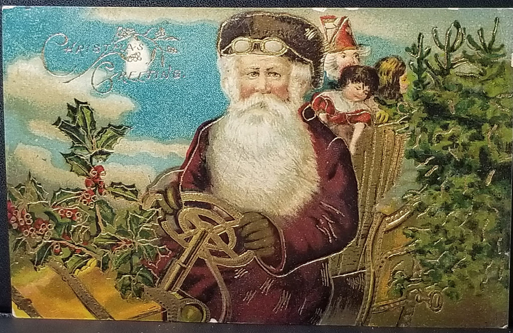 Christmas Postcard Old World Santa Claus in Maroon Robe and Goggles Driving Car Loaded with Tree & Gifts Gold Highlights